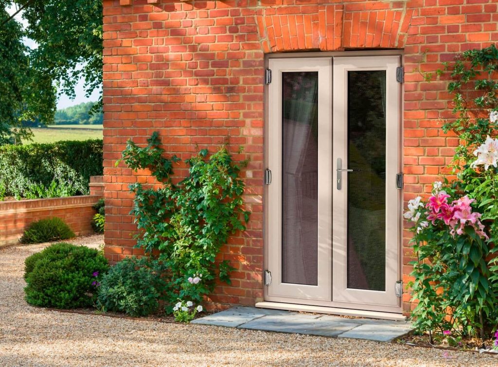 French doors on a brick house with surrounding greenery.